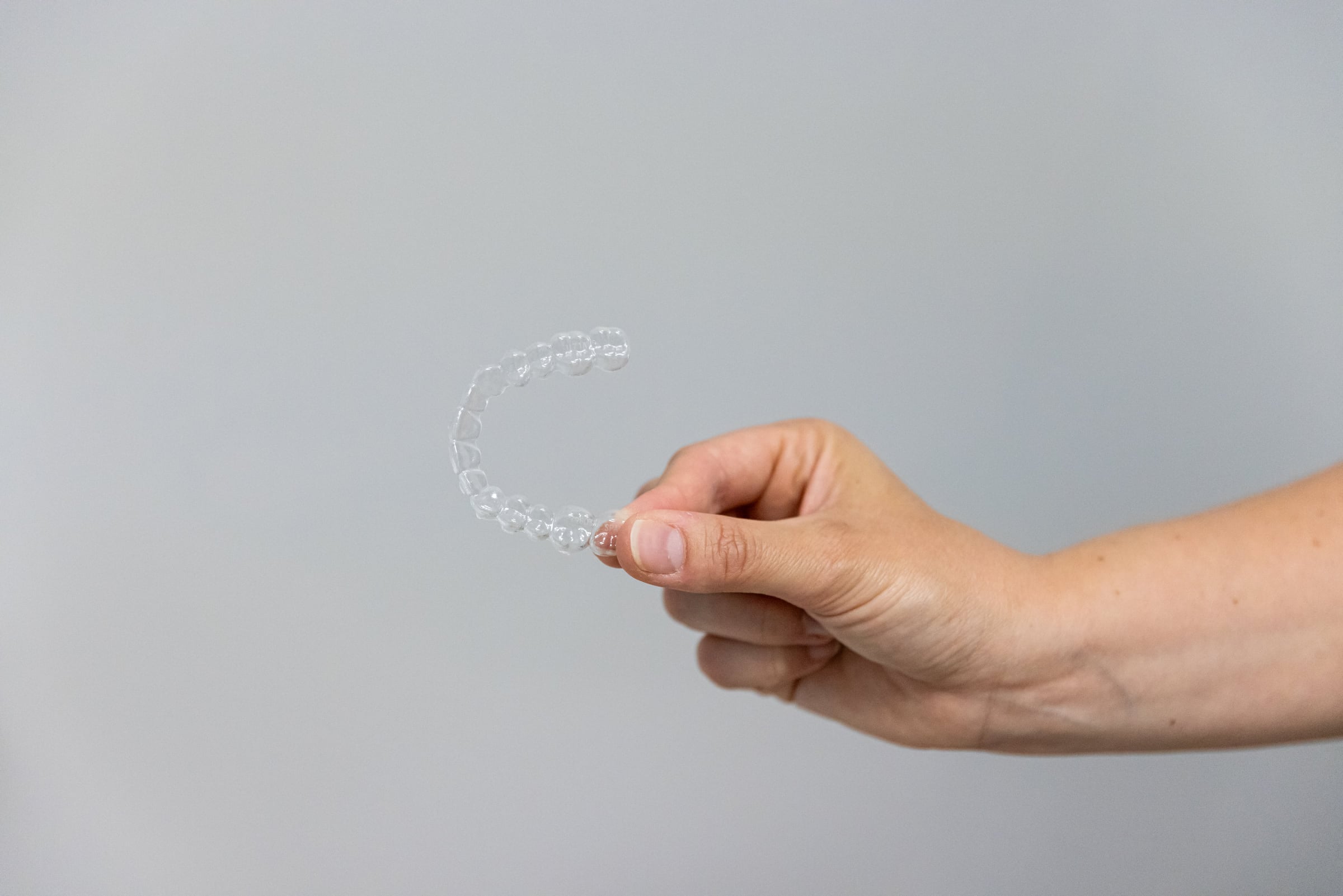 Une gouttière d'alignement transparente tenue entre deux doigts