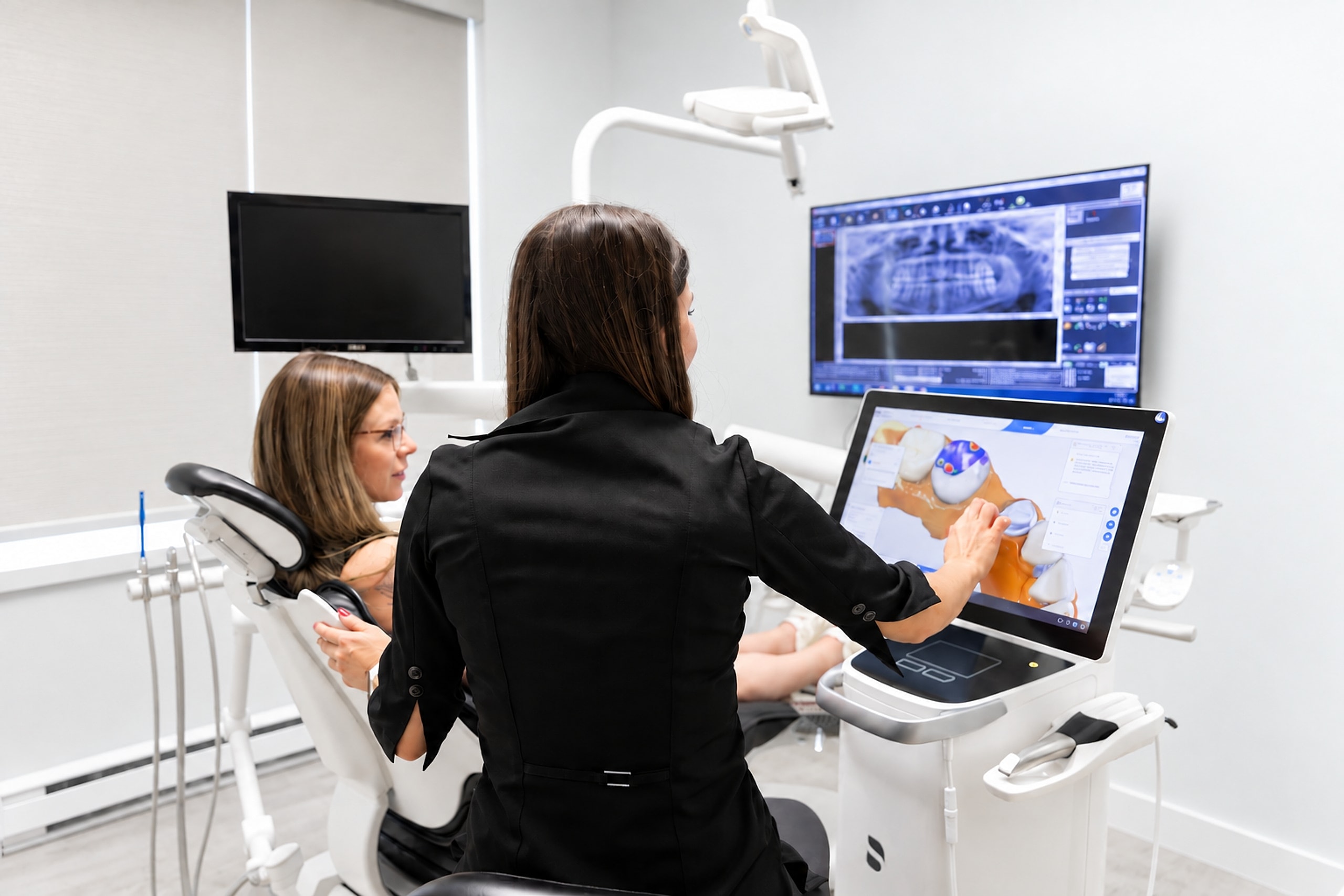 Une dentiste explique une empreinte numérique 3D à sa patiente, l'écran à côté d'elles